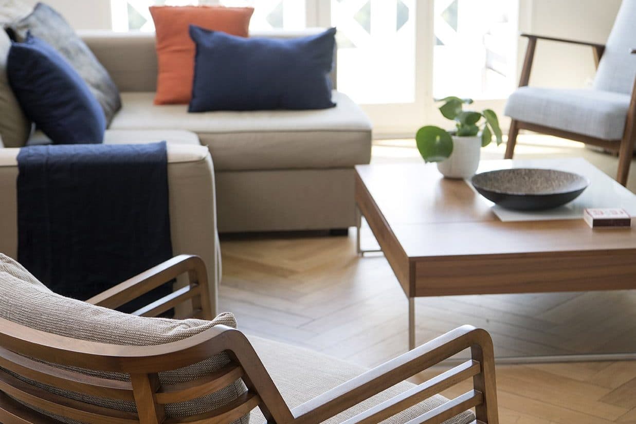 Salon avec canapé d'angle et fauteuils en bois, appartement avec vue sur les quais
